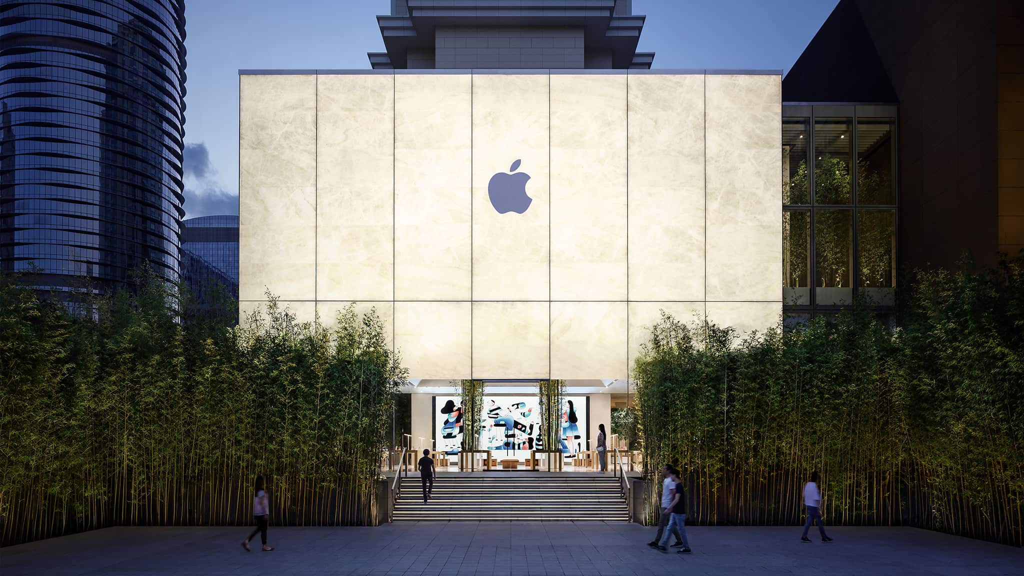 Exterior view of the Apple Cotai Strip storefront, featuring a unique 2-storey cubic shape with facades made of first-of-kind composite lamination of glass and natural stone that glows from with in when lit.
